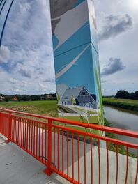 Brückenpfeiler mit Bild, auf dem ein Haus ist, im Hintergrund die Zwickauer Mulde